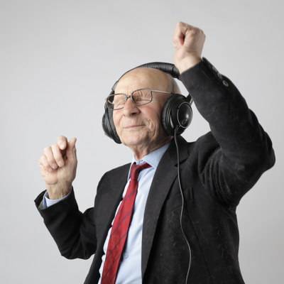 Ein älterer Herr im Anzug mit roter Krawatte mit Kopfhörer hat Spaß bei einer Audioausstellung.
