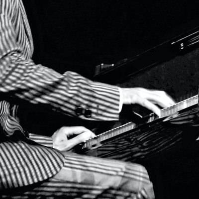 Ein Jazzpianist in einem gestreiften Jacket spielt Klavier.