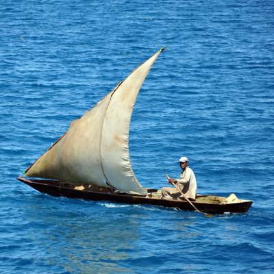 Ein Fischer mit einer Dau, einem ortsüblichen Segelboot, auf dem Meer.