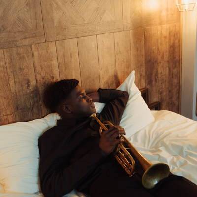 Ein Musiker liegt nachdenklich in einem Hotel auf einem Bett.