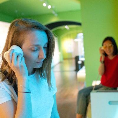 Zwei Mädchen lauschen aufmerksam einem Audioguide bei einer Audioausstellung.
